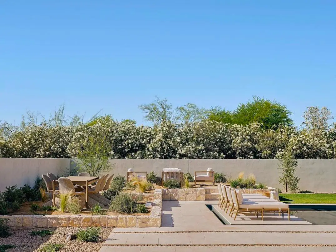 Desert courtyard with stone seating terraces, planting, and poolside lounge chairs